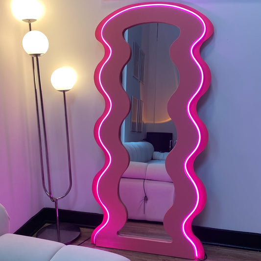 Neon pink wavy mirror in a room with a light blue sofa and floor lamps.